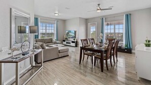 A spacious living area with a dining table, sofa, and TV. - Spacious 4BR Vista Cay Retreat near Universal (Orlando)