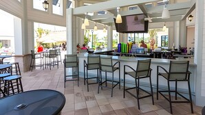 A spacious outdoor bar area with high ceilings and large windows, featuring multiple seating arrangements and a television screen. - 4BR Storey Lake Home, Sleeps 10 (Kissimmee)