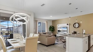 A modern living room with a dining area, a kitchen, and a large window. - 4BR Storey Lake Home, Sleeps 10 (Kissimmee)
