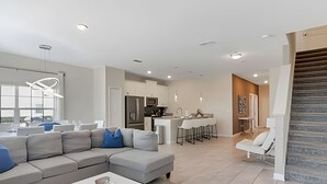 Een moderne woonkamer met een modulaire bank, een salontafel en een keuken op de achtergrond.