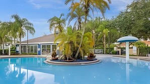 A swimming pool with a tropical garden and a covered seating area. - 3BR Lucaya Village Home Near Disney (Kissimmee)