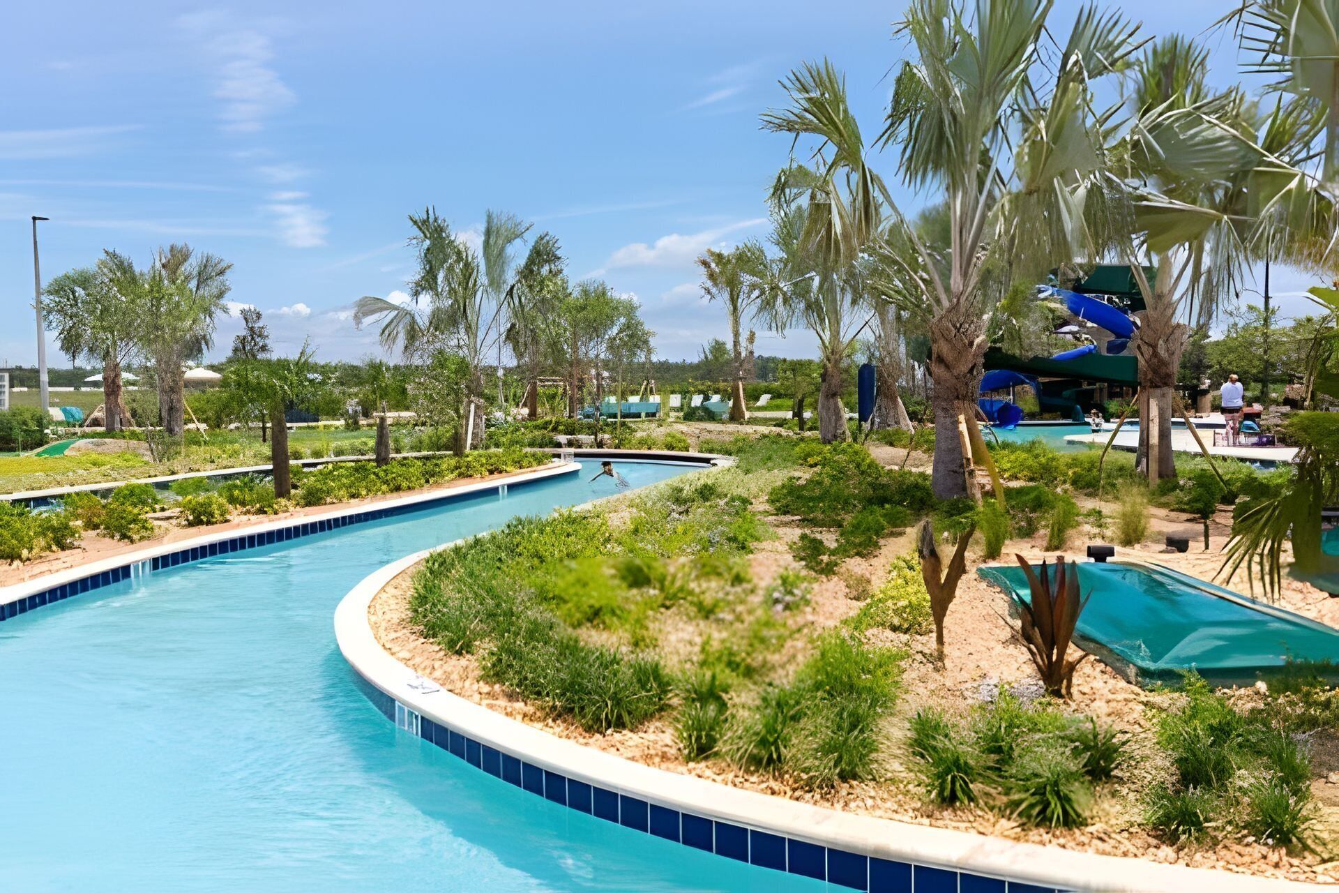 A pool area with multiple swimming pools, palm trees, and a water slide.