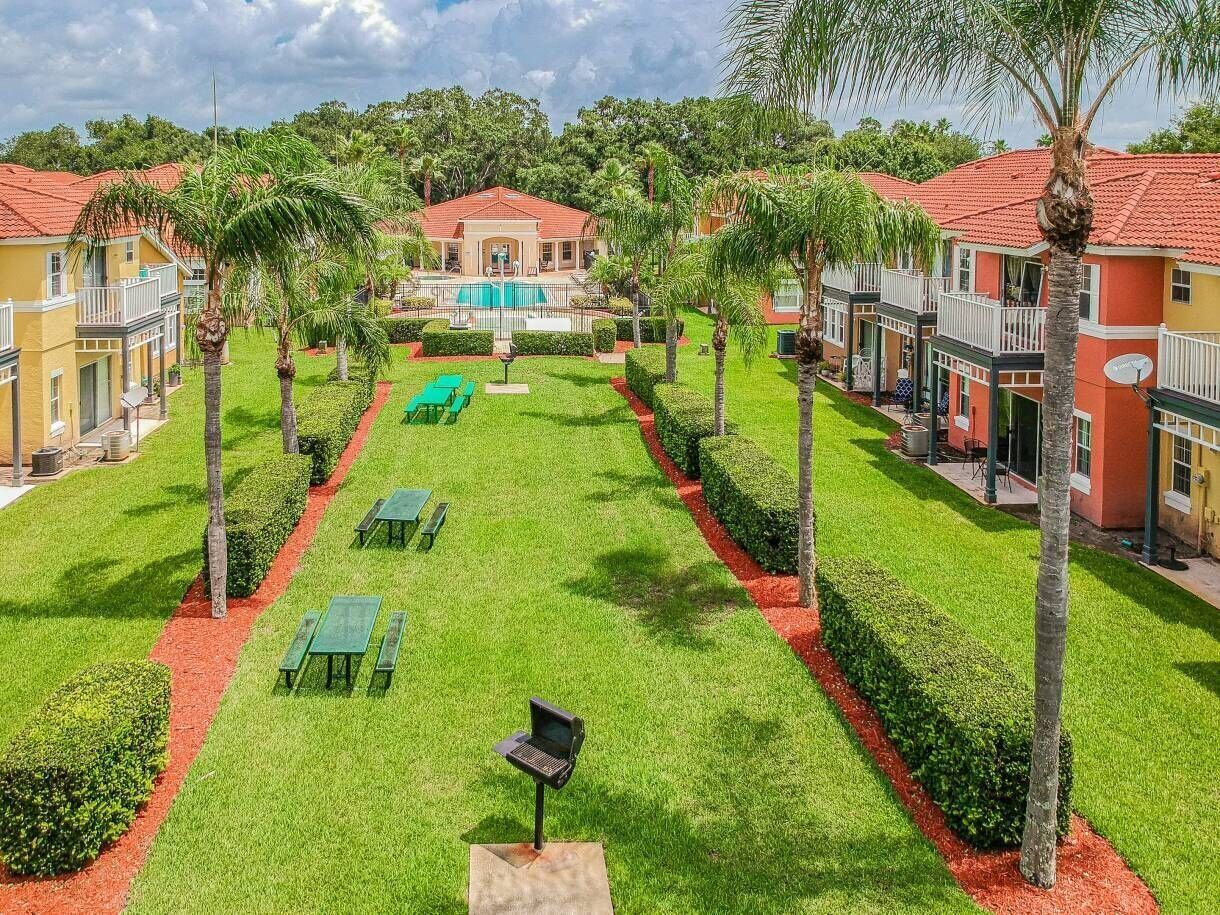 A well-maintained courtyard with a swimming pool, palm trees, and outdoor seating areas.