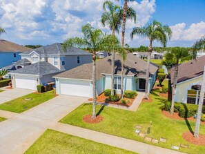 A residential area with houses featuring front yards, palm trees, and a clear sky. - 4BR Lake Berkley Home, Private Pool (Kissimmee)