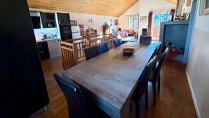 Eine geräumige Küche mit Holzausstattung, ein Essbereich mit großem Tisch und eine hohe Decke mit freiliegenden Balken.