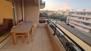 A balcony with a table and chairs, a view of a street with cars, and buildings in the background. - Comfortable stay in the heart of La Seyne-sur-Mer (La Seyne-sur-Mer)