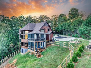 Ein großes Holzhaus mit Balkon, umgeben von einem eingezäunten Garten und dichtem Wald.