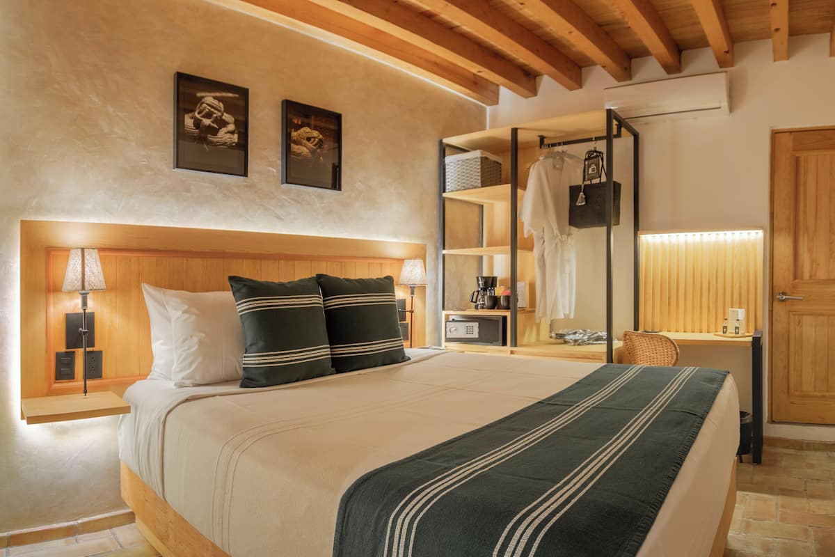 Un dormitorio con cama, mesita de noche, lámpara y un armario de madera.