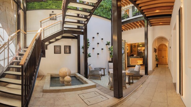 A spacious interior with a central staircase, a reception area, and a seating area with a fountain. - Casa Ziña (Oaxaca)
