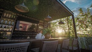 An outdoor bar area with hanging pendant lights, a large potted plant, and a view of the sky. - Casa Ziña (Oaxaca)
