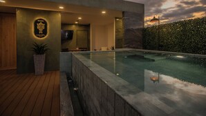 A modern hotel with a swimming pool, a wooden deck, and a well-lit entrance. - Casa Ziña (Oaxaca)