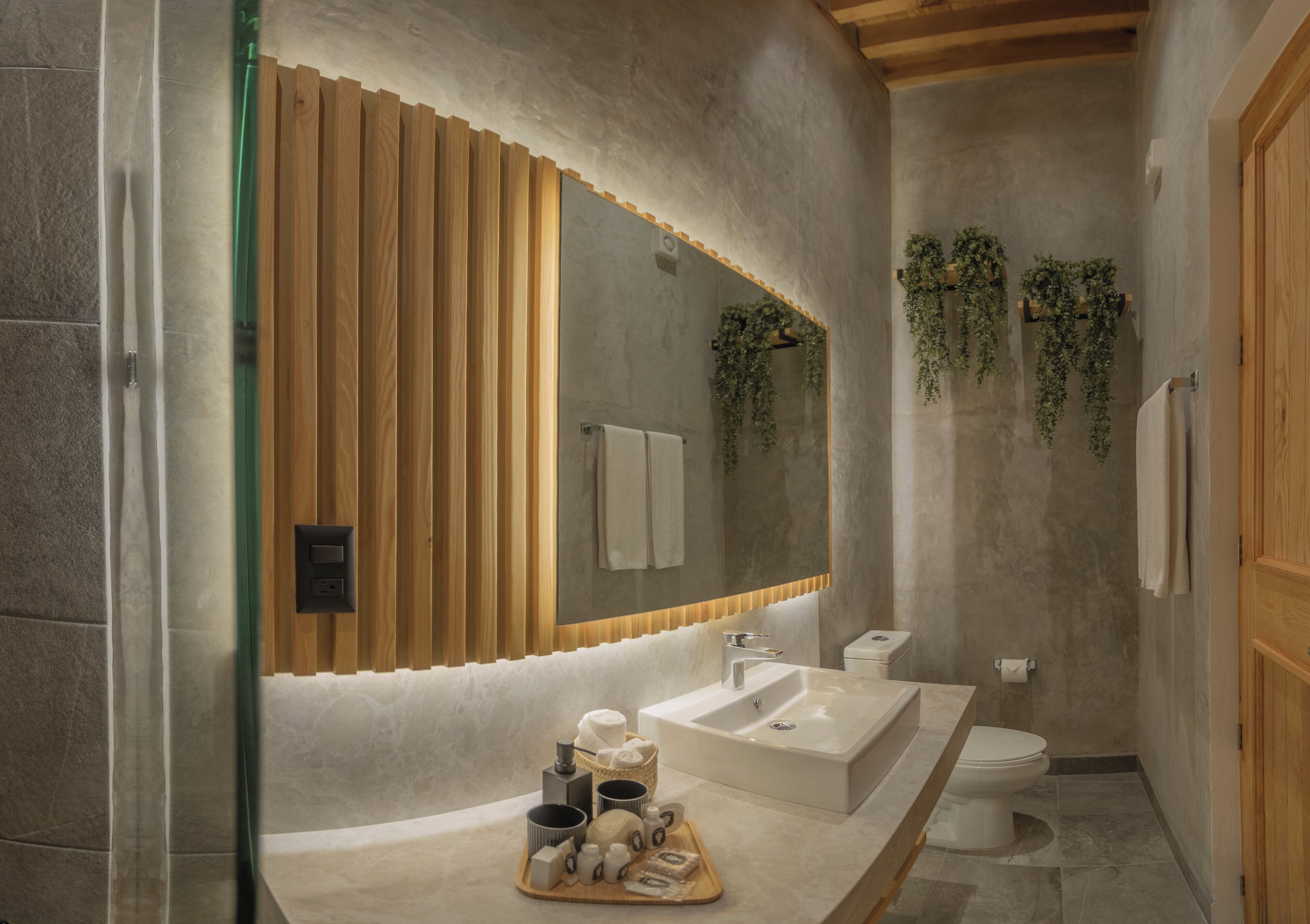 A modern bathroom with a large mirror, wooden paneling, a sink, and a toilet.