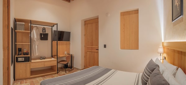 Un dormitorio con cama, escritorio, silla, armario y televisor.
