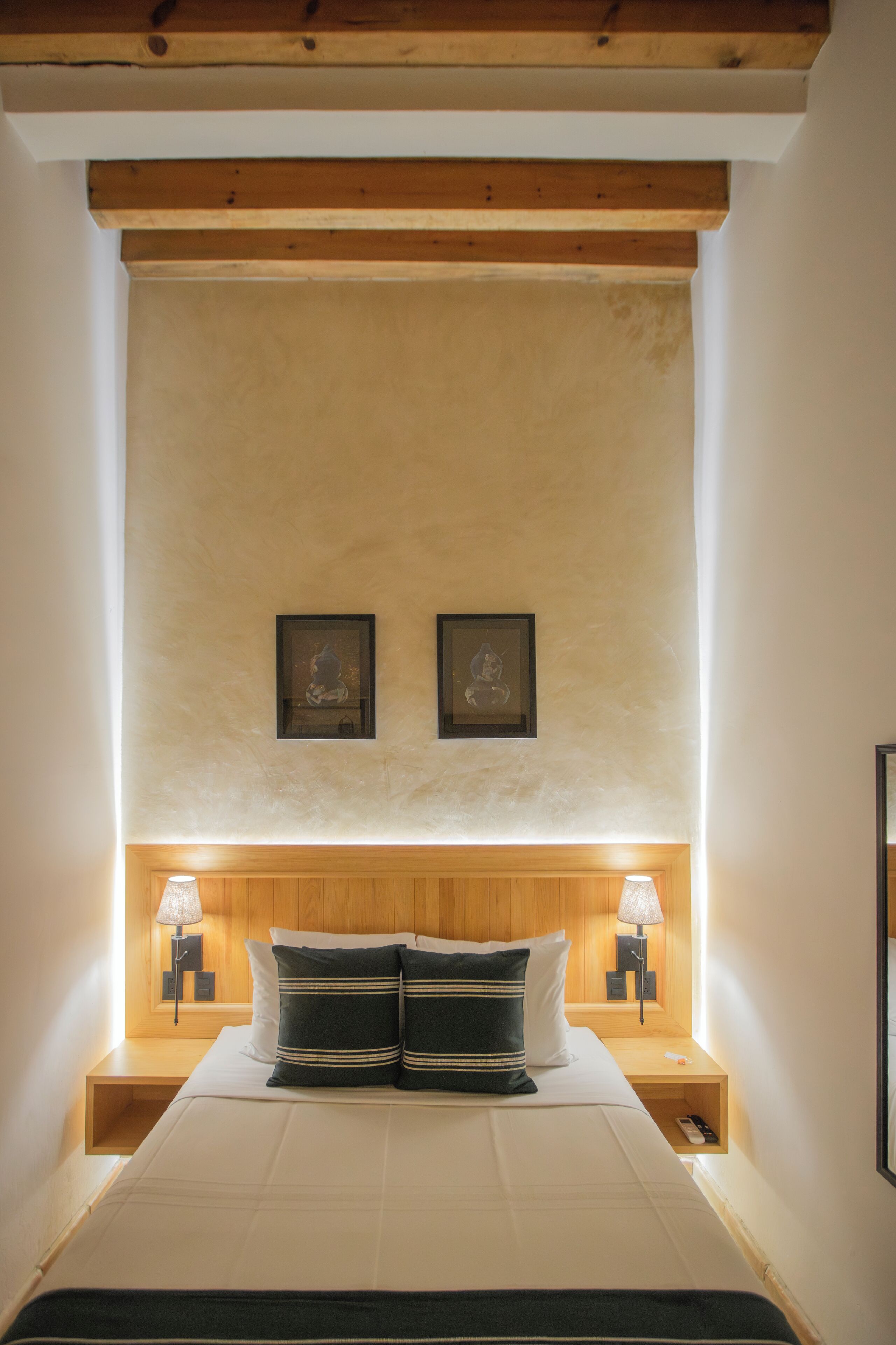 A bedroom with a large bed, two bedside tables with lamps, and framed pictures on the wall.