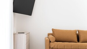 A room with a beige sofa, a flat-screen TV mounted on the wall, and a wooden cabinet. - Apartment in Plebiscito int 11 (Napoli)