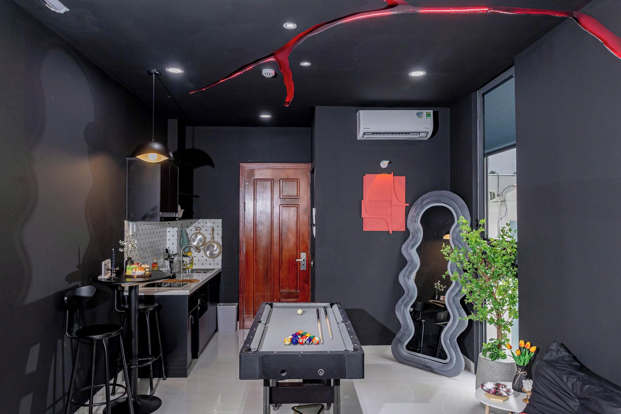 A modern kitchen with a pool table, bar stools, and a dining area.