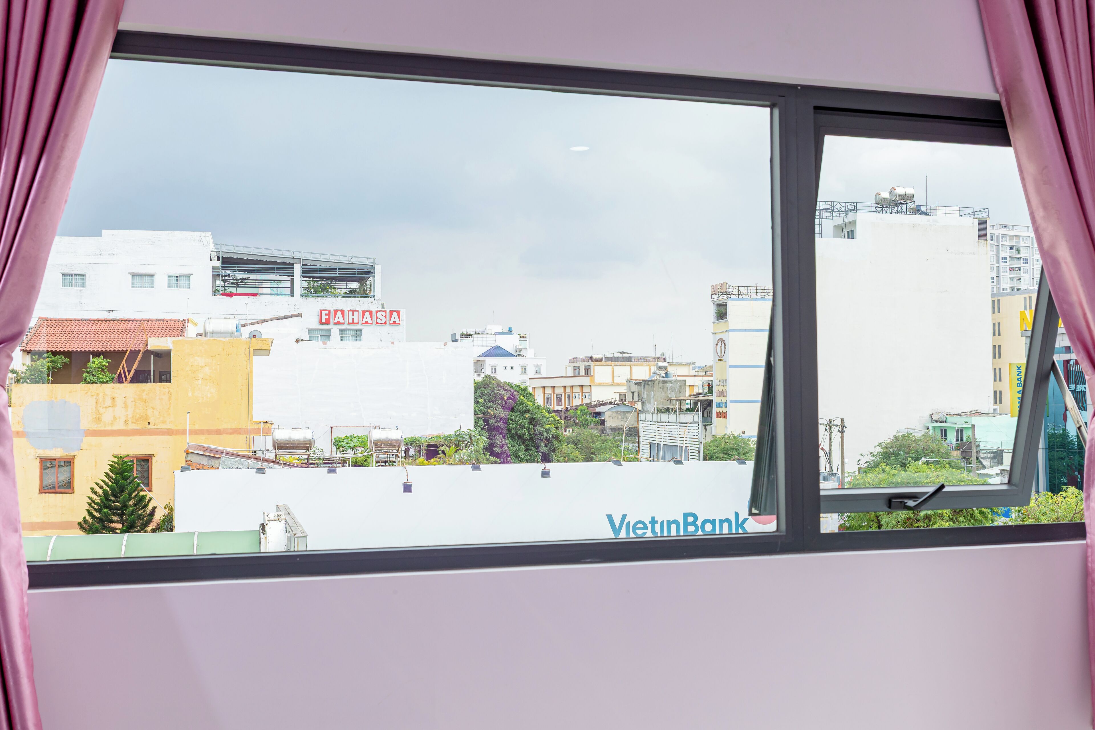 Una ventana con vista a un paisaje urbano, incluyendo edificios y el rótulo de un banco.