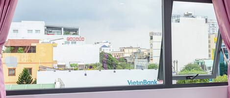Una ventana con vista a un paisaje urbano, incluyendo edificios y el rótulo de un banco.