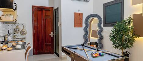 A pool table with balls, a wooden door, and a potted plant.