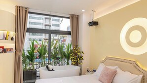 Una camera d'albergo con un letto grande, una vasca da bagno e vista sulla città dalla finestra.