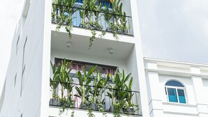 Un edificio a più piani di colore bianco, con balconi su ogni piano, alcuni dei quali adornati con piante.