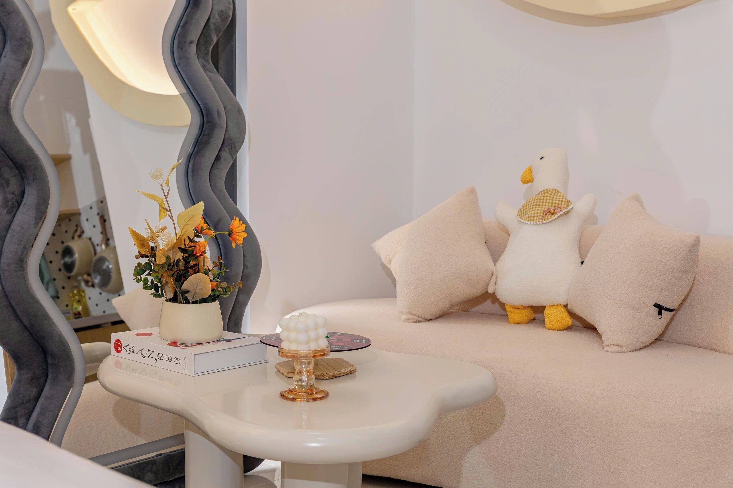 Uma sala de estar moderna com um sofá branco, uma planta decorativa e um brinquedo macio no sofá.
