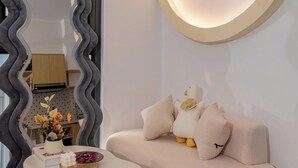 Un soggiorno moderno con un divano ad arco, uno specchio decorativo e un condizionatore d'aria a parete.
