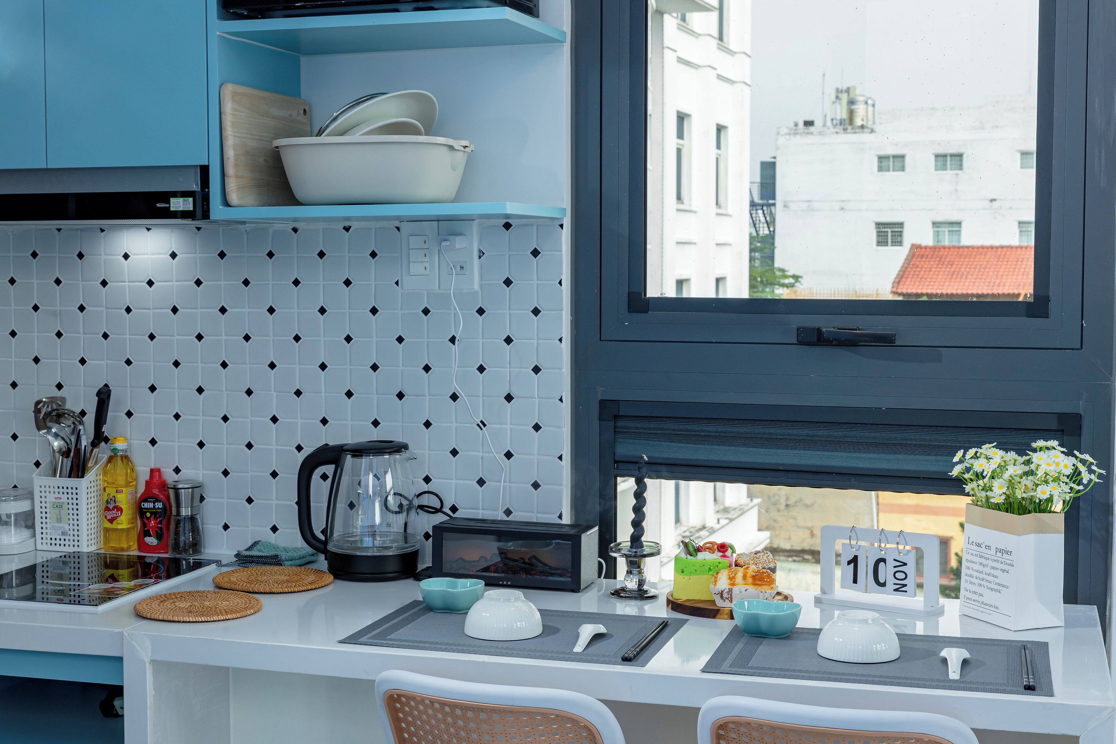 A modern kitchen with blue cabinets, a tiled backsplash, and a window with a city view.