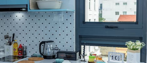 A modern kitchen with blue cabinets, a tiled backsplash, and a window with a city view.