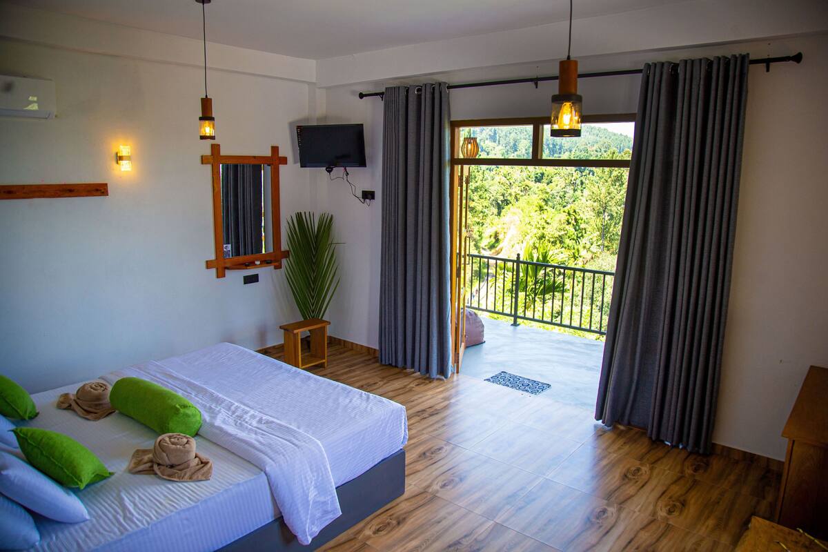 Un dormitorio con cama, televisor, planta y balcón con cortinas.