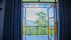 An open door leading to a balcony with a view of a forested hillside. - Tunnel Top Inn Ella (Ella)