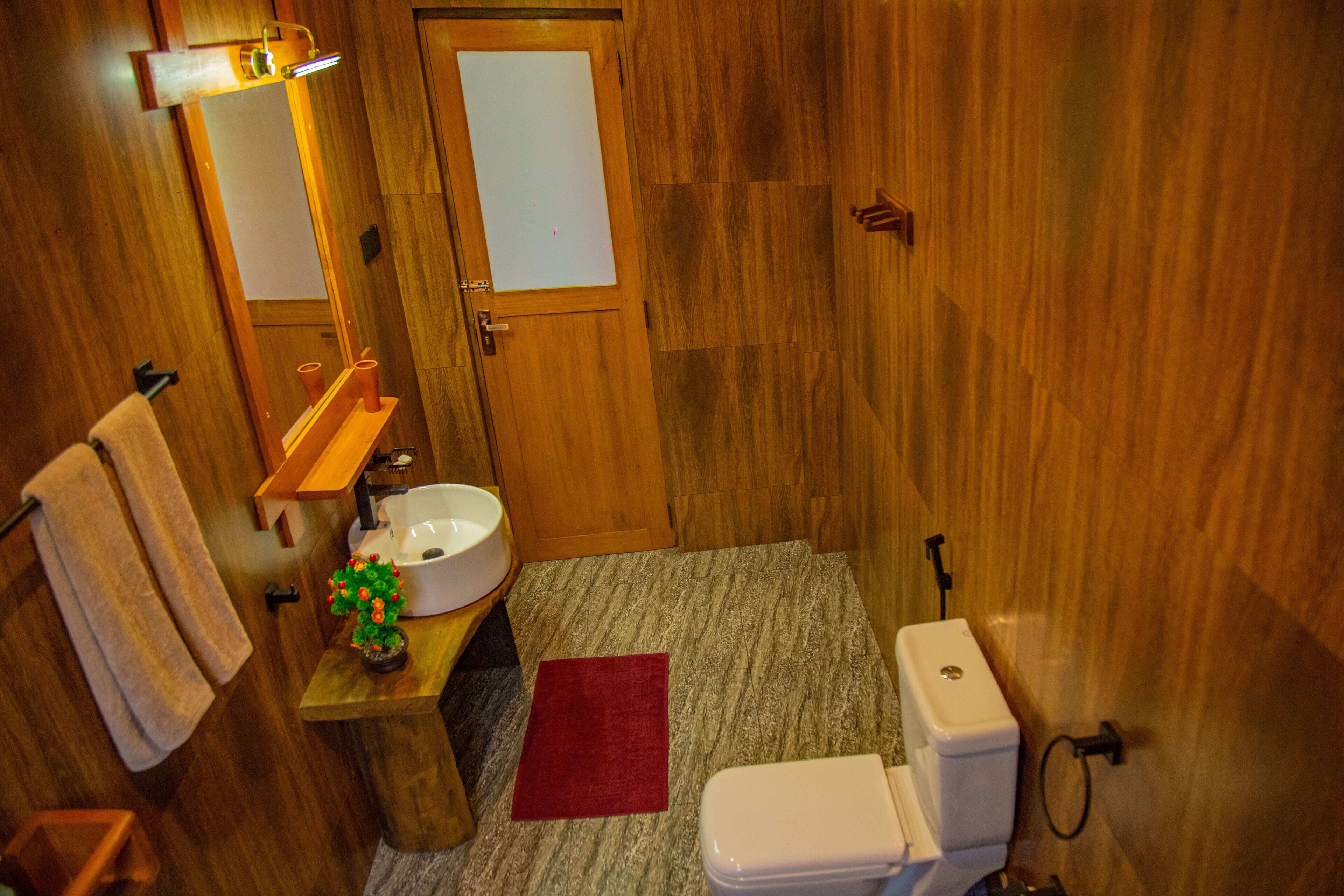 A wooden bathroom with a sink, mirror, and toilet.