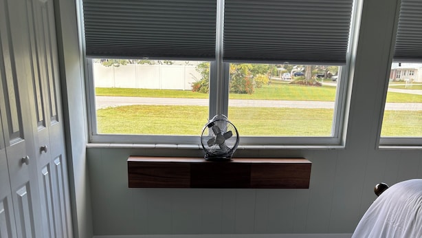 Une chambre avec une grande fenêtre, un ventilateur et un sol en marbre.