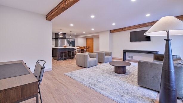 Una sala de estar moderna con comedor, cocina y televisor montado en la pared.