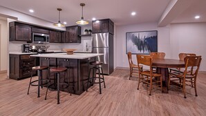 Una cocina moderna con armarios de madera oscura, electrodomésticos de acero inoxidable y una isla central con taburetes.