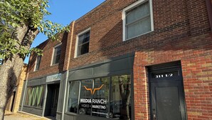 Un edificio de ladrillo de dos pisos con un escaparate que dice 'Media Ranch Video x Marketing'.