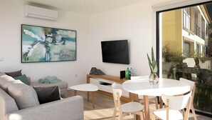 Ett modernt vardagsrum med en grå soffa, ett soffbord, ett matbord med stolar, en platt-TV och en stor, abstrakt tavla.