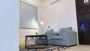 A living room with a sofa, a round coffee table, a lamp, and a patterned rug. - Maskn Al Bader (Madinah)