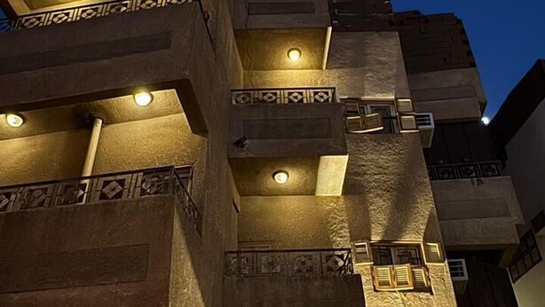 A multi-story building with balconies, each illuminated by a single light fixture. - Maskn Al Bader (Madinah)