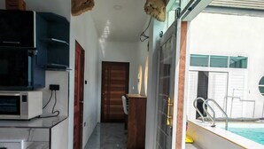 A modern kitchen with a built-in microwave, a TV, and a dining area with a wooden table and chairs. - Fantastic 3-bedroom with AC in charming in Pattaya Chon Buri (Chon Buri)