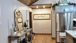 A kitchen with wooden ceiling beams, a stainless steel refrigerator, a wooden console table with candles, and a 'grateful' sign on the wall. - Murphy House at Pickwick (Tishomingo County)