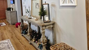 A room with a wooden ceiling, a console table with decorative items, a mirror, and a window with a white frame. - Murphy House at Pickwick (Tishomingo County)