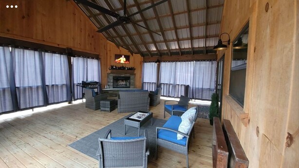 A covered outdoor area with wooden walls, a fireplace, and seating arrangements. - Murphy House at Pickwick (Tishomingo County)