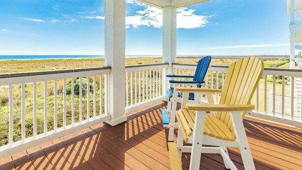 A wooden deck with white railings and two Adirondack chairs facing a beach view. - Bright Beachfront Retreat, Elevator, Dog Friendly, Quick Beach Access (Galveston)