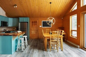 Ein Holzblockhaus-Interieur mit Küche, Essbereich und einem großen Fenster.