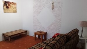 Ein Wohnzimmer mit einer Couch, einer Holzbank, einem kleinen Tisch und einer Wand mit Struktur.