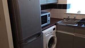 Eine kompakte Küche mit Kühlschrank, Mikrowelle und Waschmaschine.