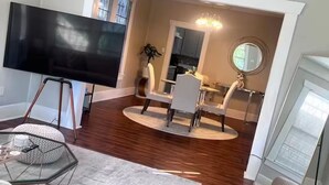 Ein Wohnzimmer mit Flachbildfernseher, einem Glastisch und einer Sitzecke mit rundem Teppich.