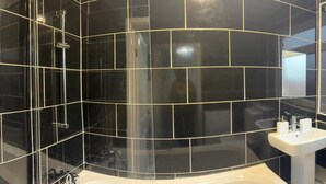 A modern bathroom with a curved shower enclosure, a white sink, and a mirror. - Ground Floor Property - Sleeps 2 - Parking - Garden (Jarrow)