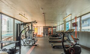 A gym with treadmills, weight machines, and a mirrored wall. - Modern Accommodations in a Building With a Pool in the Heart of SP - Yhes (São Paulo)